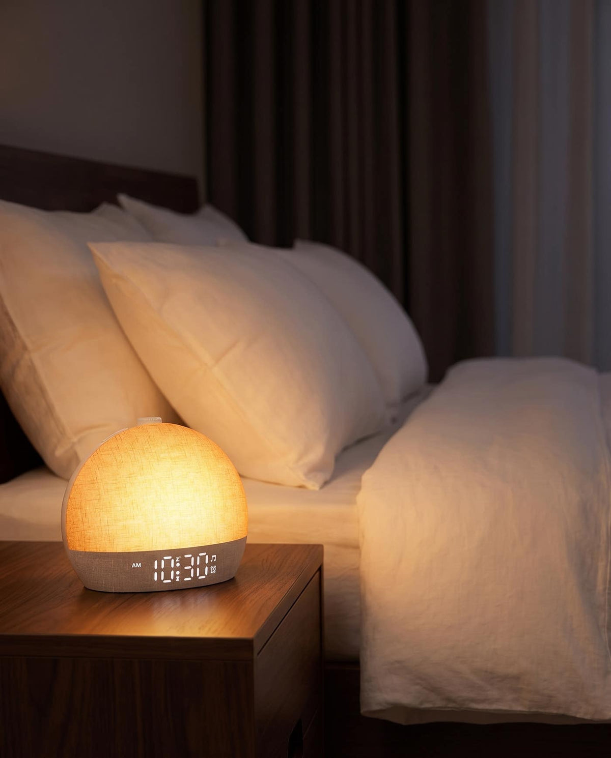 Easylight sunrise alarm clock glowing a warm pre-dawn orange on a nightstand in a dark bedroom